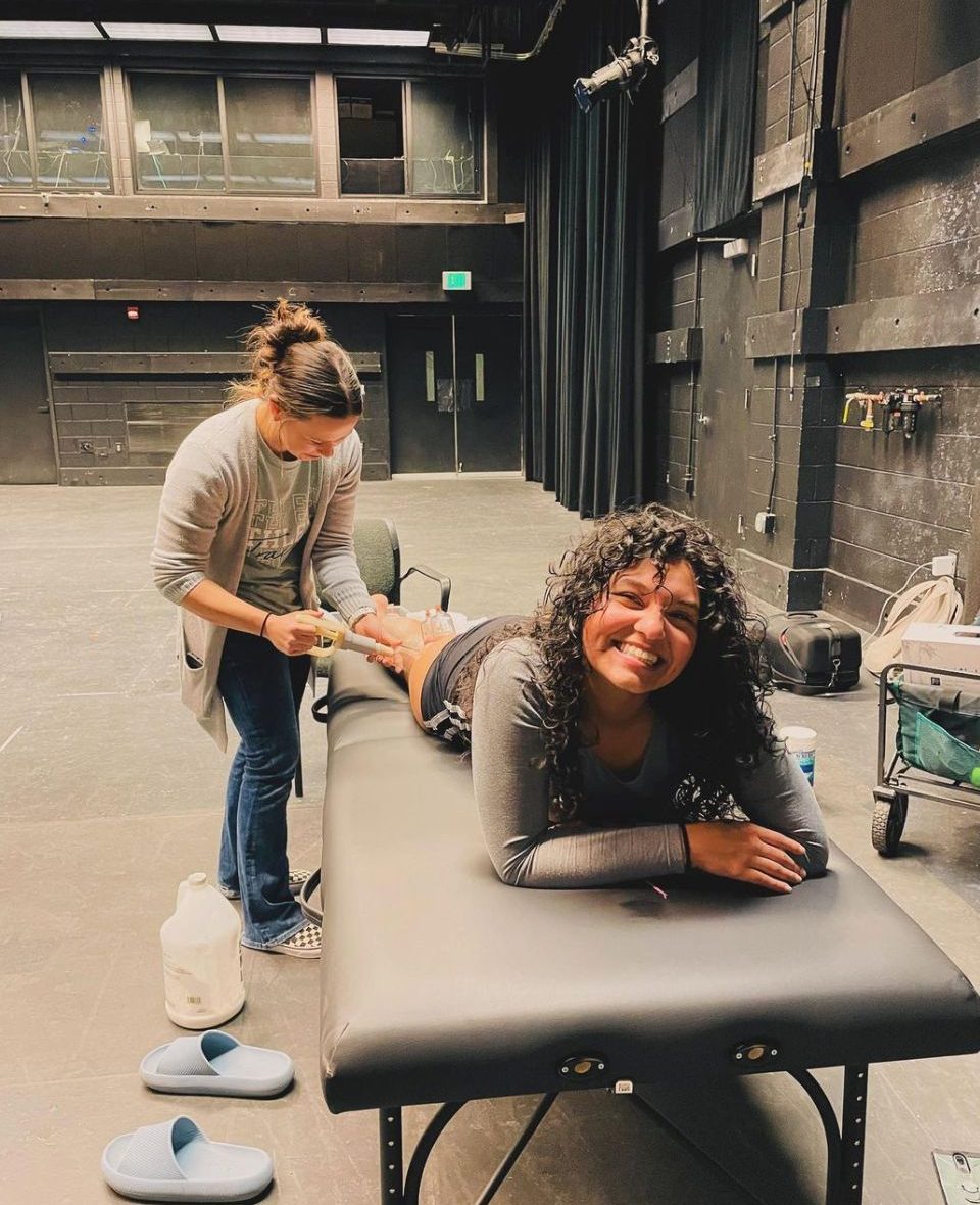 Student laying on exercise table with a PT working on muscles to prepare for the fall dance concert 