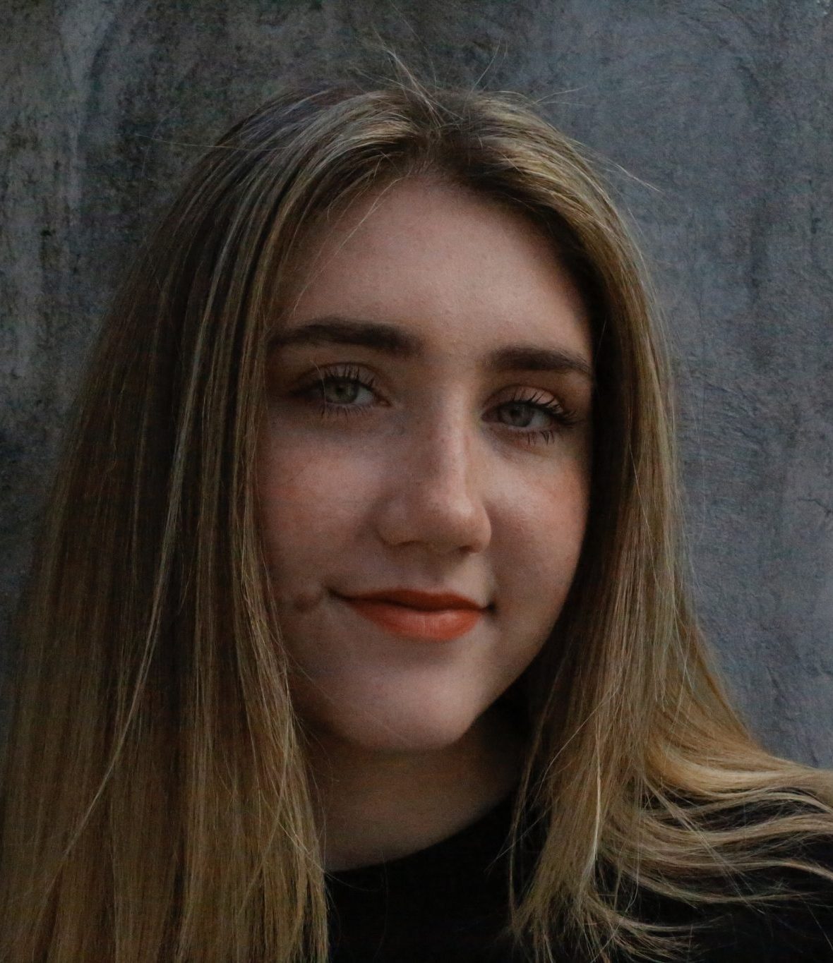 Headshot of a female student with light brown hair against a grey wall