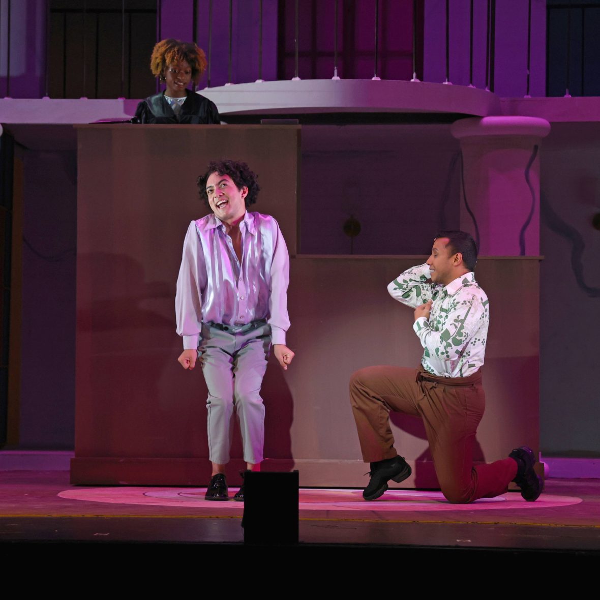 Male student smiling in a ruffle top on stage as part of Legally Blonde The Musical 