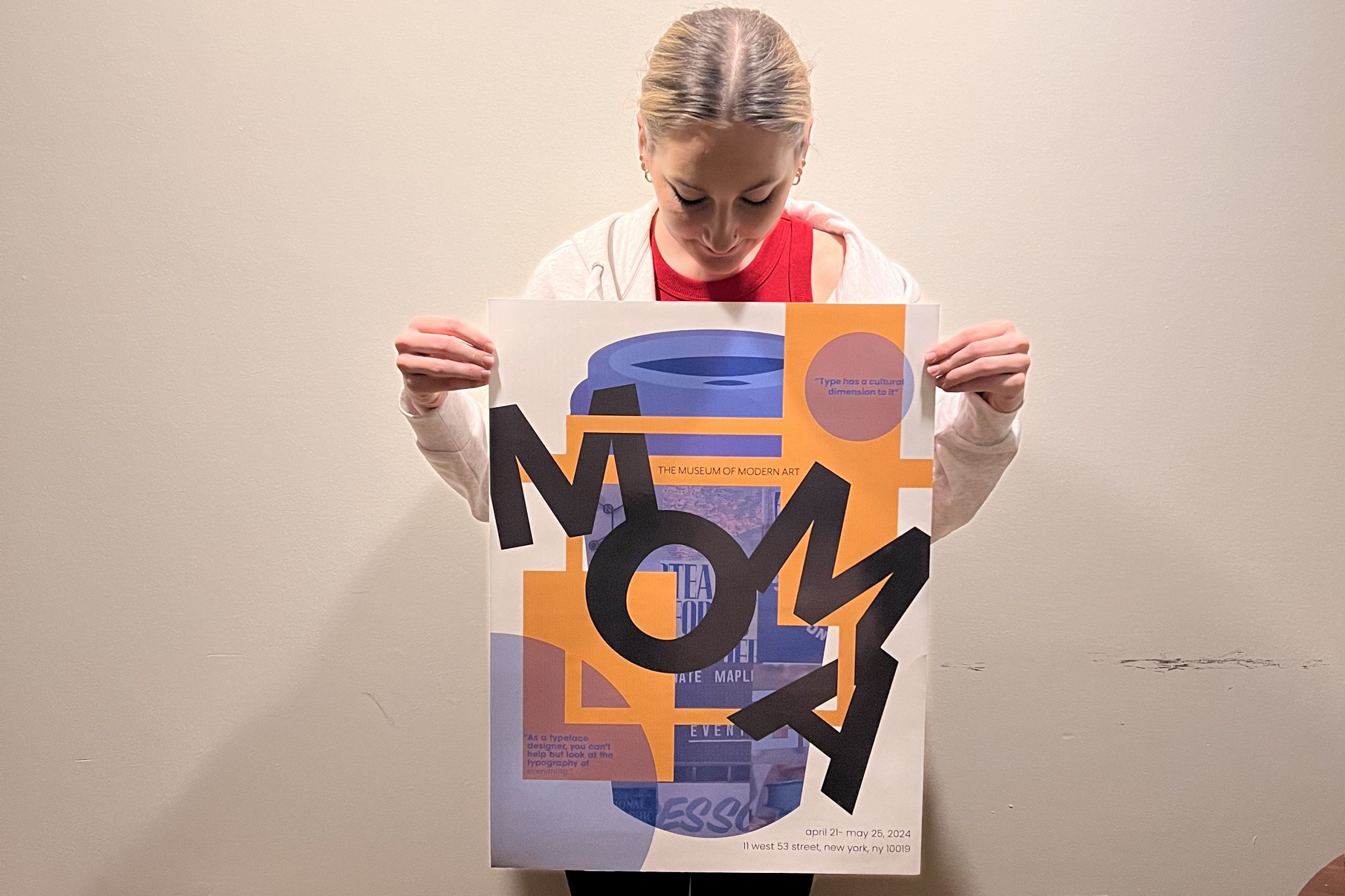 a student holding up her artwork against a white wall