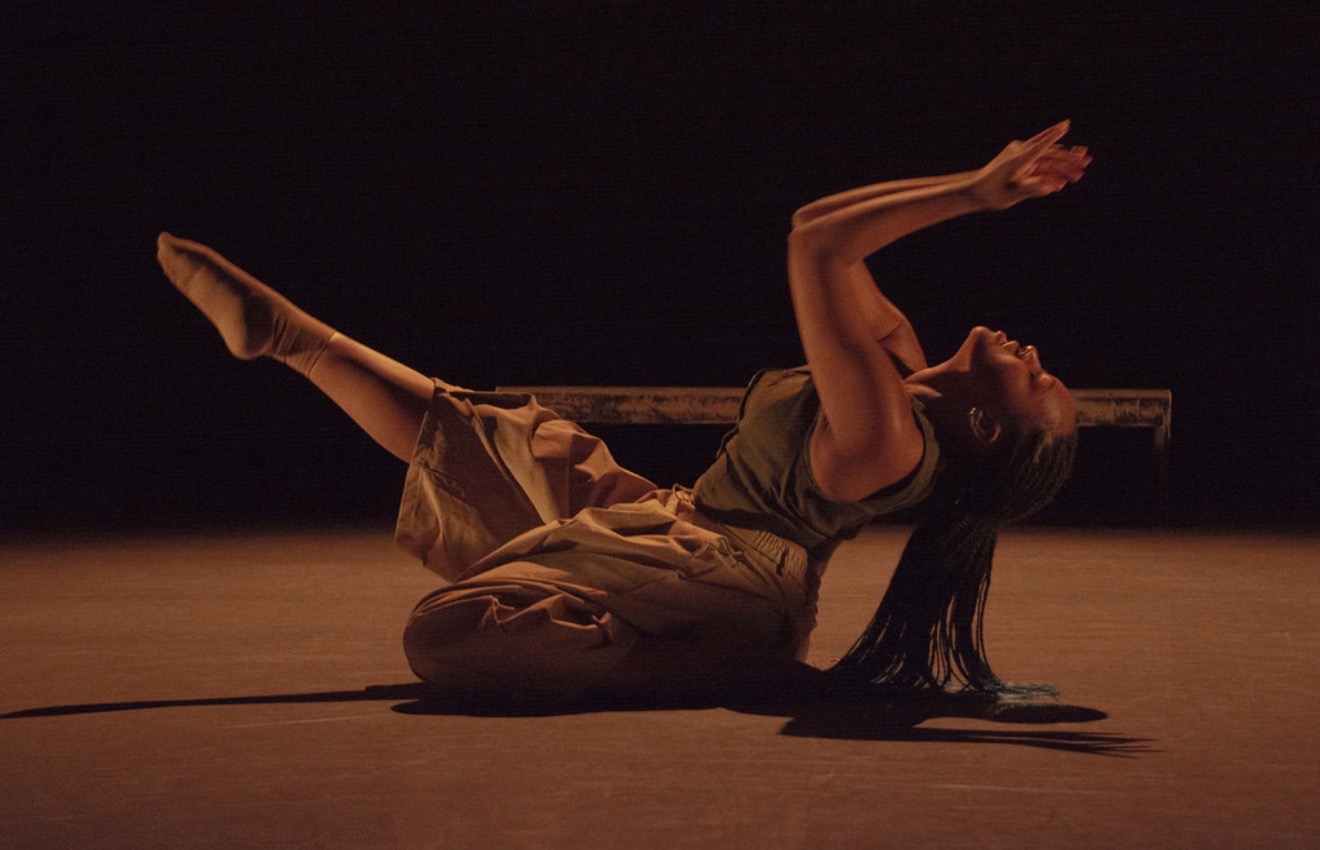 Natalia on a dark stage with her hands above her head