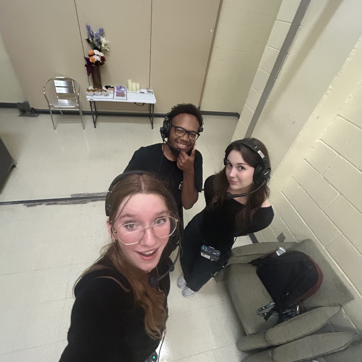 three theatre students standing backstage with headsets on