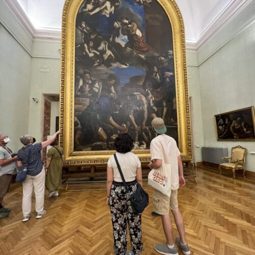 two students looking at a large framed painting in a museum in Italy
