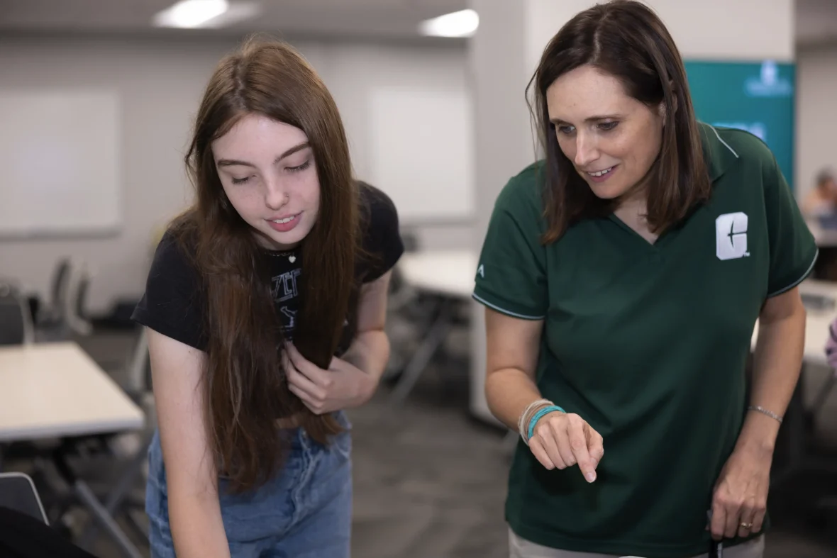 student and faculty member look at something together